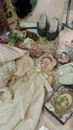 an old fashion doll is laying on the floor next to other antique clothing and shoes