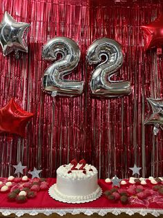 a cake and balloons are on a table in front of the number twenty two sign