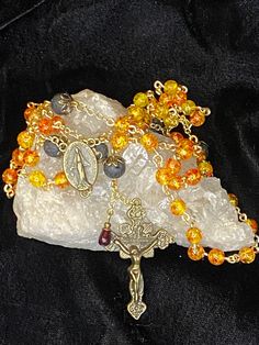 The exquisite Sunset rosary is a symbol of faith and beauty, meticulously handcrafted to elevate your spiritual experience.  Czech glass radiates a mesmerizing play of colors reminiscent of a blazing sunset.  The vibrant hues of red, orange, and yellow ignite a sense of passion and devotion, bringing warmth and inspiration to your prayers.  The glass is paired with volcanic lava beads for the application of essential oils, such as myrrh or frankincense, for a complete immersive experience.  Also features a single red glass teardrop bead hung down by the crucifix as a reminder of the redemptive blood our Lord and Savior shed for us. Comes in a pretty organza pouch.   All my rosaries are handcrafted with love and the best materials available.  They are meant to be treasured for years to come Spiritual Crucifix Necklace With 8mm Beads, Spiritual Necklace With Miraculous Medal And Round Beads, Adjustable Spiritual Rosary With Miraculous Medal, Spiritual Crucifix Jewelry With 8mm Beads, Spiritual Round Beads Rosary For Jewelry Making, Gold Spiritual Rosary For Meditation, Spiritual Rosary With Round Beads For Meditation, Spiritual Rosary With 108 Beads And Crucifix, Spiritual Rosary For Meditation With Round Beads