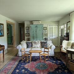 a living room filled with furniture next to a wooden table on top of a rug