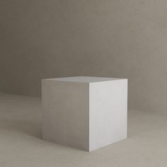 a white square object sitting on top of a cement floor in front of a wall