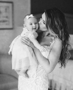 a woman holding a baby in her arms and kissing it's face on the cheek