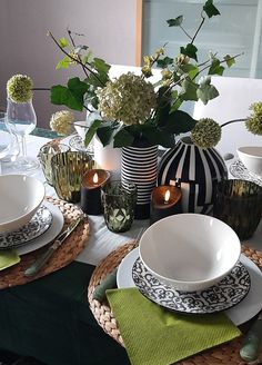 the table is set with plates, bowls and vases on it's centerpiece