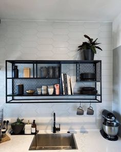 a kitchen with white counter tops and black shelving above the sink is filled with pots, pans, and utensils