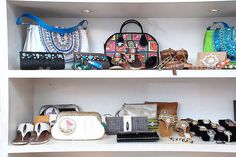 several purses and handbags on shelves in a room with white shelve