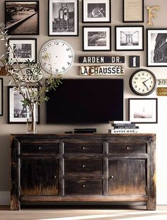 a person holding up an open book with pictures on the wall and clocks above it