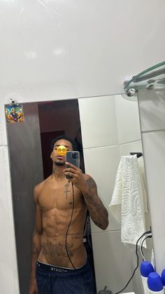 a man with no shirt is taking a selfie in front of a bathroom mirror