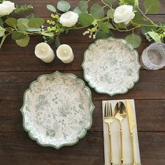 the table is set with plates, silverware and white flowers on top of it