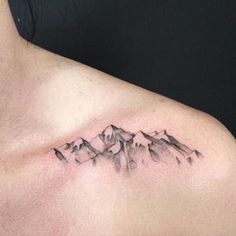 a tattoo on the chest of a man with mountains in the backgrouund