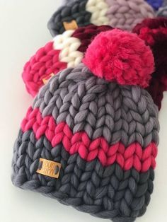 several knitted beanies with pom poms on the top one is multicolored