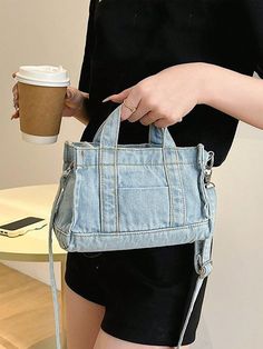 a woman is holding a denim bag and coffee