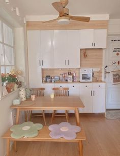 a wooden table sitting under a ceiling fan next to a white refrigerator freezer mounted to the side of a wall