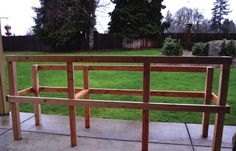 a wooden bench sitting on top of a cement floor next to a lush green field