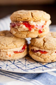 four cookies with strawberry filling on a blue and white plate