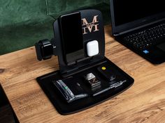 an open laptop computer sitting on top of a wooden desk next to a charger