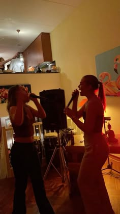 two women are singing into microphones in a living room