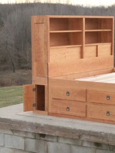 a bed that is made out of wood and has drawers on the bottom shelf next to it