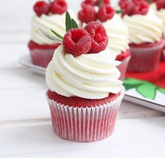 red velvet cupcakes with white frosting and fresh raspberries on top