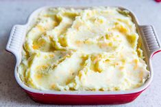 a red dish filled with mashed potatoes on top of a table