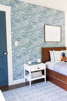 a child's bedroom with blue and white wallpaper, a wooden headboard, and a bed