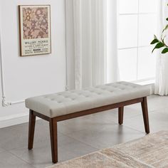 a white bench sitting in front of a window next to a rug and potted plant