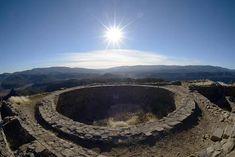 the sun shines brightly over an old stone structure on top of a rocky hill