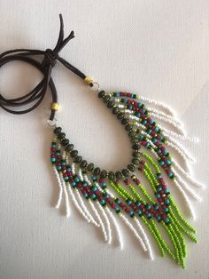 Strands of white, lime green, dark green, turquoise and hot pink seed beads with small gold crystals are attached to small gold plate disks.  The disks are separated by turquoise stones.  The necklace is finished with a brown leather cord with gold plate beads.  The tied length is about 22", the longest strands are about 3.5" I can change to gold or black chain if you wish.  Please indicate the desired length.  Or, I can put a hook closure at the back of the neck instead of the ties.  Let me know what changes you would like. Tagua Necklace, Cowgirl Necklaces, Gold Crystals, Western Necklaces, Bear Pendant, Fringe Necklace, Necklace Gemstone, Black Chain, February Birth Stone