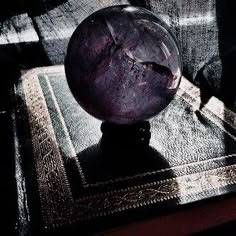 a glass ball sitting on top of a rug next to a window sill in the dark