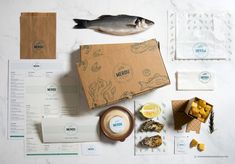 an assortment of fish and other food items on a white table with paper napkins