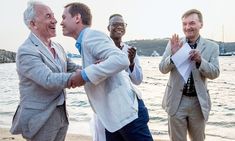 three men are standing on the beach with their hands in each other's pockets