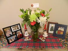 a vase filled with flowers sitting on top of a table next to pictures and frames