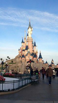 people walking in front of a castle with turrets on it's roof and walkway