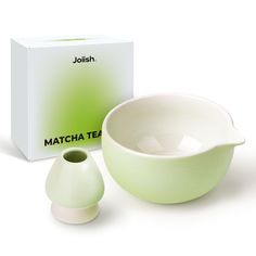 a green and white porcelain bowl next to a boxed matcha tea cup on a white background