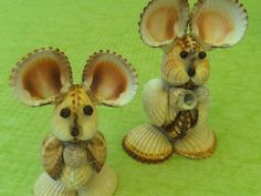 two figurines of mice sitting on seashells with their tails curled up