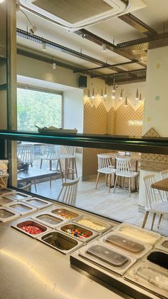 the inside of a restaurant with tables and chairs, food trays on the counter