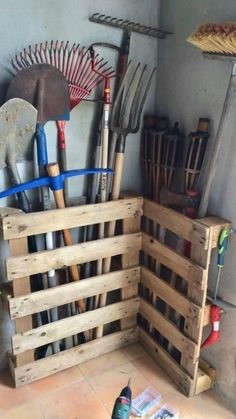 a bunch of gardening tools in a wooden crate on the floor next to a wall