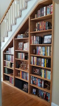 a bookshelf filled with lots of books next to a stair case