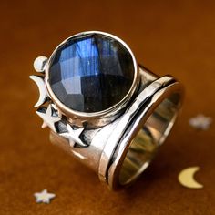 This unique sterling silver spinner ring has a giant labradorite gemstone surrounded by celestial stars and a moon. This labradorite stone truly is a show stopper! Just wait until you see it catch the sunlight and watch all the colors of this stone shine. Labradorite is commonly known as the stone of things ‘unseen.’ It provides energetic and spiritual protection while also warding off negative vibes. This showstopper is perfect for any spiritual boho girlie! Material: Genuine Sterling Silver 92 Black Tourmaline Jewelry, Celestial Stars, Negative Vibes, Full Finger Rings, Raw Stone Jewelry, Rose Quartz Jewelry, Ear Jacket Earring, Fidget Rings, Spiritual Protection