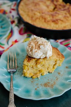 a piece of cake on a blue plate next to a fork and pie dish with whipped cream