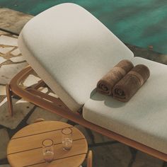 towels and glasses are sitting on a chair next to the pool