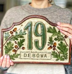 a woman is holding up a plaque with the number 19 debowa on it