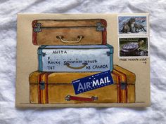 an animal is sitting on top of a suitcase and some stamps are in front of it