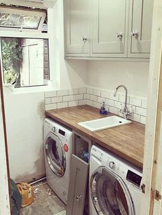 a washer and dryer sitting in a kitchen next to each other on top of a wooden counter