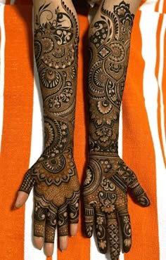 two hands with henna tattoos on them, one is showing off the intricate design