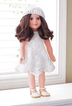 a doll with long hair wearing a white dress and headband standing on a window sill