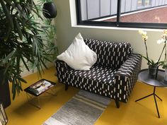 a black and white couch sitting next to a window on top of a yellow floor