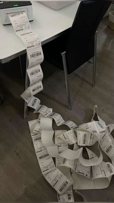 a pile of paper sitting on top of a wooden floor next to a computer desk