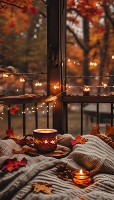 an autumn scene with candles and leaves on the bed, in front of a window