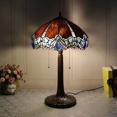 a table lamp sitting on top of a table next to a vase filled with flowers