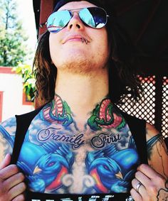 a man with tattoos on his chest wearing sunglasses